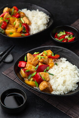 Sweet ad sour chicken served with steamed rice in black bowl