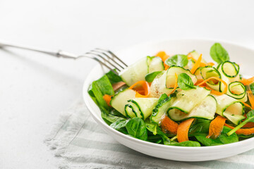 Vegetable  salad from spinach leaves, cucumbers and carrots. On white concrete table. Close-up. Copy space.