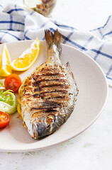 Delicious grilled dorado or sea bream fish with salad, spices, grilled dorada on a plate.