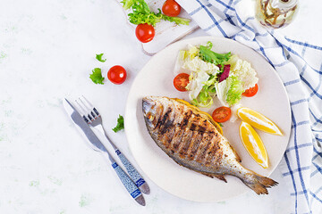 Delicious grilled dorado or sea bream fish with salad, spices, grilled dorada on a plate. Top view, overhead, copy space