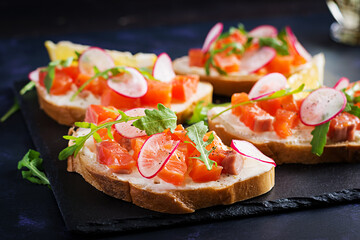 Sandwich with salted salmon for healthy breakfast on dark background. Fish menu.