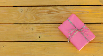 Yellow gift box with golden bow on vintage boards. Happy Holidays.