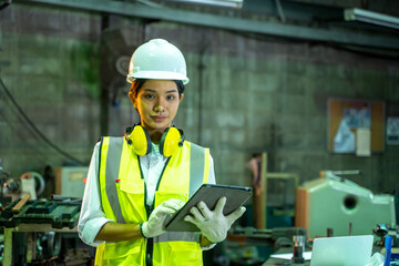 Female technician worker using a digital tablet working and checking production in a large industrial factory.