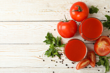 Glasses with tomato juice, tomatoes and spices on wooden background