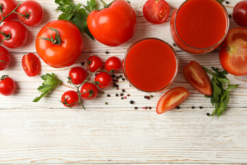 Glasses with tomato juice, tomatoes and spices on wooden background