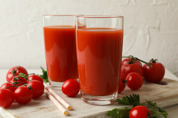 Board with tomato juice and tomatoes on white textured background