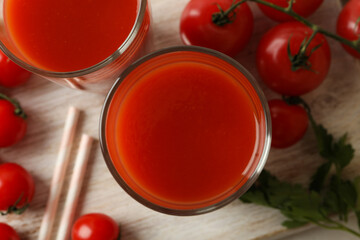 Board with glasses of tomato juice and tomatoes, close up