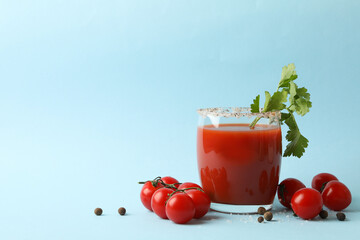 Glass of Bloody Mary and tomatoes on blue background