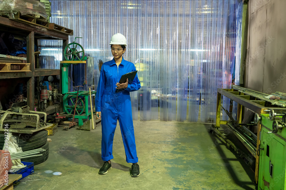Poster female industrial worker in protective uniform working and checking machine in a large industrial fa