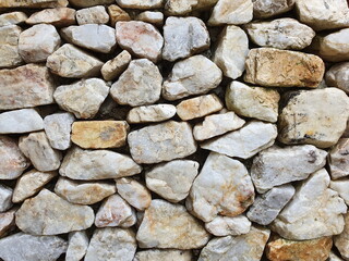 Gray-white stone and granite - of various sizes, arranged neatly as a wall or fence. wall composes of various size of stone

