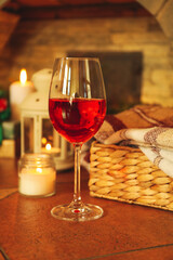 Glass of red wine and Christmas accessories against fireplace