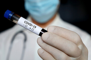 Doctor in mask holding test tube with covid-19 blood sample. Coronavirus test, medical analyzing