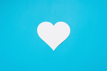 White heart cut from paper on a blue background. Flat lay, top view. Love concept, valentine's day, greeting poster