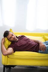 Man sleeping on yellow sofa at home, stock image