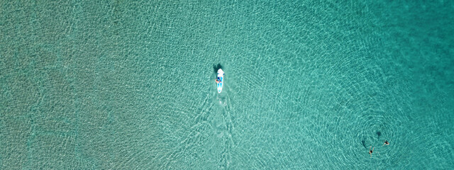 Aerial drone ultra wide photo of couple practice SUP or Stand Up Paddle board in tropical exotic...