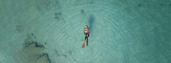Aerial drone top down ultra wide panoramic photo of spearfishing scuba diver in tropical exotic shallow bay with turquoise clear waters