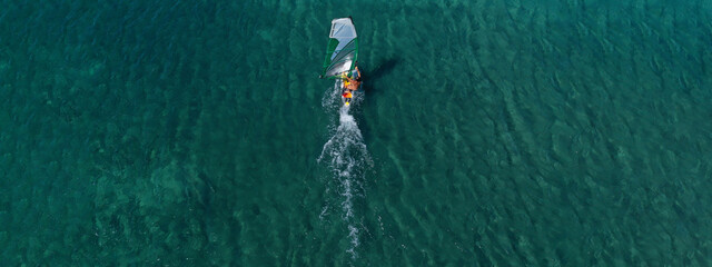 Aerial drone ultra wide top view photo of fit man practising wind surfing in Mediterranean bay with crystal clear emerald sea