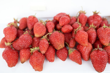 A lot of strawberries lie on a white windowsill. Top view