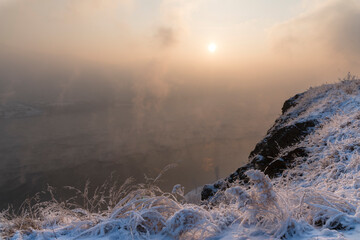 Evening on the river. Beautiful winter landscape with frost. Sunset, fog, haze