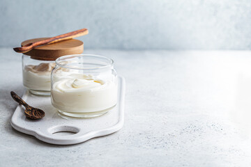 Homemade yogurt in glass jars, light background, copy space. Yoghurt preparation concept.