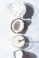 Flat lay of coconut products - milk, yogurt and chips, white background, top view. Coconut food concept.