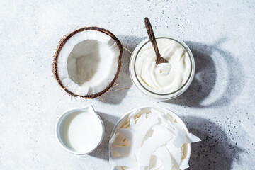 Vegan coconut products - milk, yogurt and chips, white background, top view. Coconut food concept.