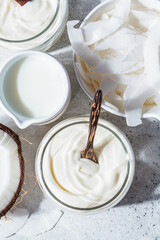 Vegan coconut products - milk, yogurt and chips, white background, top view. Coconut food concept.
