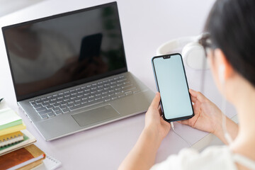 Young Asian woman is holding the phone in her hand, the phone has a white screen to be able to insert text