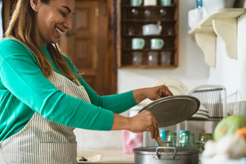 Latin mature woman cooking in old vintage kitchen - Smiling mother preparing lunch at home