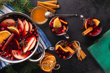 Hot wine in cooking pot and glasses with mulled wine or punch on a black textured background, top...