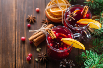 Fragrant, hot punch or mulled wine for Christmas in a glass on a wooden board and branches of a...