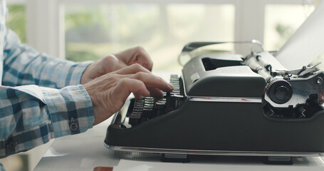 Man sitting at desk and typing on a typewriter