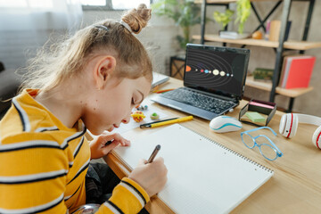 8 years old girl study Solar system sitting at the desk