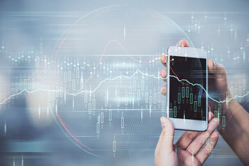 Double exposure of forex graph sketch hologram and woman holding and using a mobile device. Stock market concept.