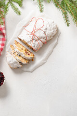 Obraz na płótnie Canvas Christmas cutted stollen with candied fruit on white table. Tasty traditional German treats. Copy space. View from above. Vertical.