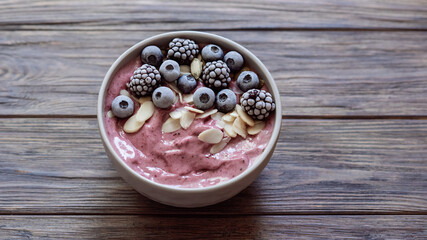 Healthy breakfast berry smoothie bowl topped with Blueberries blackberries, pumpkin seeds and almond flakes with copy space. delicious blueberry smoothie bowl. vegan raw food. Selective focus. Flatlay