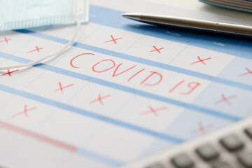 Pen lying on table with calendar with red strikethrough dates during covid19 pandemic