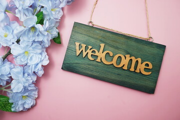 Welcome Sign and Flower Blooming Decoration on pink background