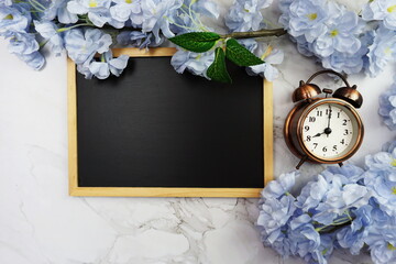 Mock-up flat lay Black board and alarm clock with flower bouquet decoration