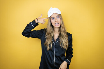 Young pretty woman wearing sleep mask and pajamas over isolated yellow background smiling and thinking with her fingers on her head that she has an idea.