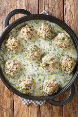 Greek meatballs with rice in yogurt sauce with lemon close-up in a plate on the table. Vertical top view from above