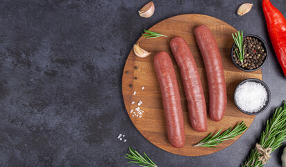 Raw meat beef sausages for grill and spicy, herbs rosemary, pepper, salt on table