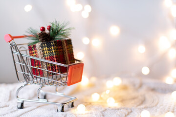 Christmas gift on a white knitted background in a shop basket