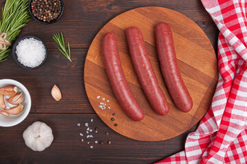 Raw meat beef sausages for grill and spicy, herbs rosemary, pepper, salt on table