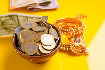 Indian rupees note,coins and gold jewelry over yellow background