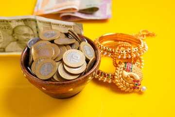 Indian rupees note,coins and gold jewelry over yellow background
