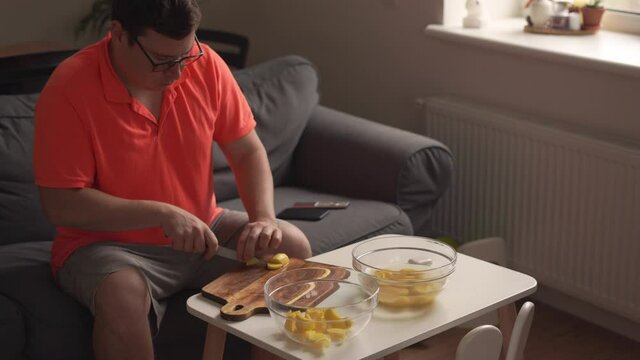 Caucasian man peeling potato at home, cooking dinner. Father or single man preparing food