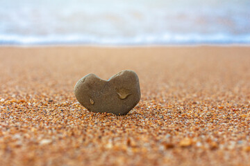 Heart shaped stone on sandy sea beach. Selective focus. Honeymoon, Valentine's Day, wedding, love concept. Copy space.