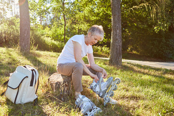 Senior woman putting on inline skates in summer