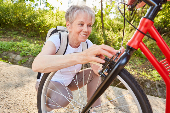 Senior woman doing DIY repair of bicycle